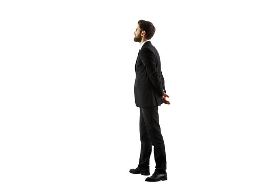 A man in a formalsuit standing in profile, hands clasped behind his back, on a white background. Business concept
