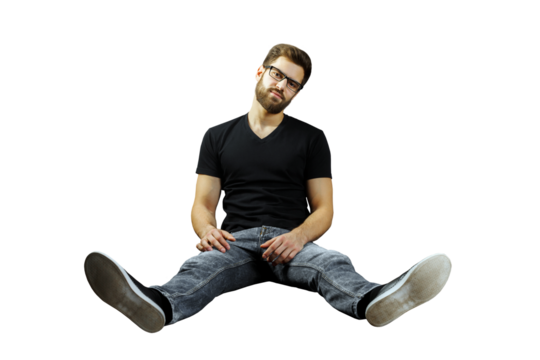Casual man with glasses sitting on the floor, legs spread and relaxed on a clean white background. Concept of casual style and modern attitude