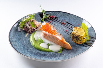 Salmon Steak with Red Caviar, Sauce, and Iceberg Lettuce on a Plate Against a White Background