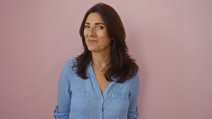 Fototapeta premium Woman smiling against pink background showcasing a middle-aged hispanic female in a blue shirt