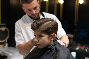 Modern Barber Cutting a Boy's Hair in a Contemporary Barbershop