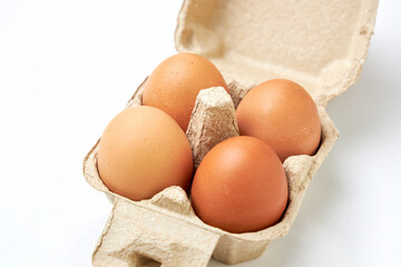 Close up of 4 fresh eggs placed in a cardboard tray molded into a package. Fresh eggs in the package isolated on a white background.