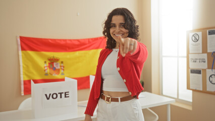 A young attractive hispanic woman in an indoor electoral college room with a spanish flag behind...