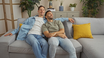 Obraz premium Two men couple relaxing on a comfortable couch in a cozy living room, emphasizing lgbtq love and family in a modern home interior setting.