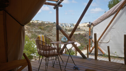 A serene camping scene with an empty wicker chair on a wooden deck under a tent, overlooking a...