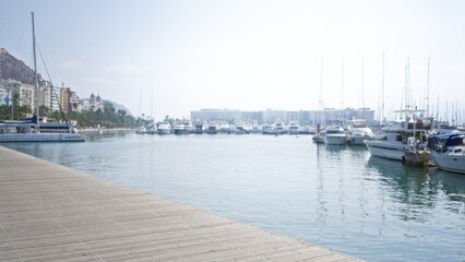 Blurred harbor scene with boats and yachts docked along a coastal city marina under a clear sky