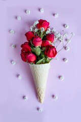 bouquet of red roses with white gypsophila in waffle ice cream cup on pink background