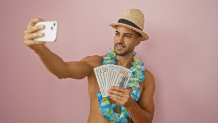 Young man with a beard in a straw hat and floral lei holding us dollars, taking a selfie against an...