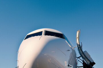 Fototapeta premium Front view of an airplane with the door open waiting for passengers to board.