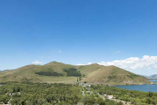 Visit the tranquil shores of Sevan Lake surrounded by lush greenery and rolling hills under a bright blue sky
