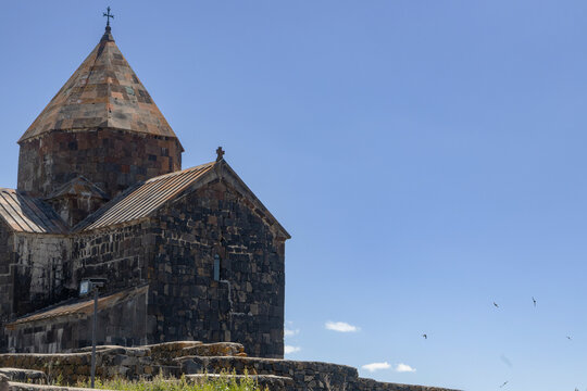 Sevanavank monastery showcases ancient stone architecture under the bright sun amidst Armenias serene landscape.