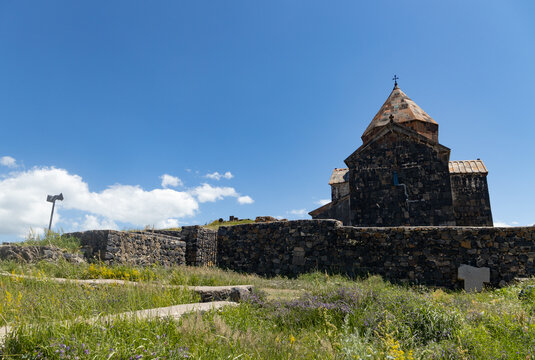 Explore the serene beauty of Sevanavank Monastery, surrounded by blooming grass under a clear blue sky in Armenia.