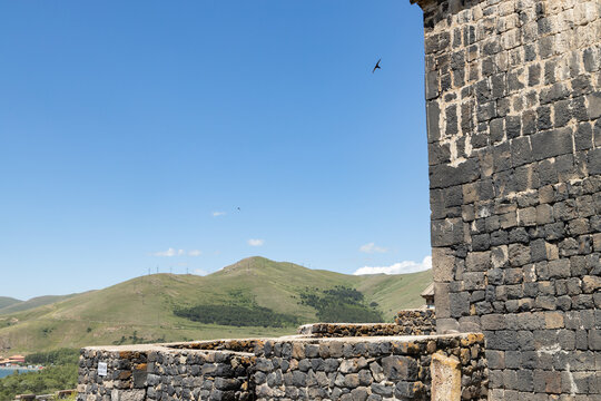 Visitors admire the ancient architecture of Sevanavank monastery surrounded by lush hills under a clear blue sky