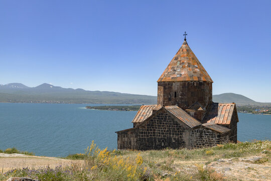 Sevanavank Monastery stands majestically overlooking Lake Sevan, surrounded by serene nature and distant mountains.