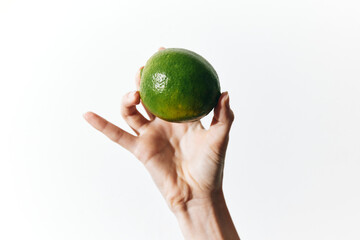 Person holding a green lime on a white background with copy space for text