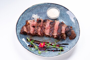 Medium-Rare Grilled Steak Sliced with Sauce on a Plate on a White Background
