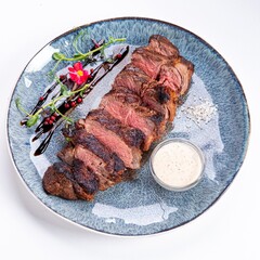 Medium-Rare Grilled Steak Sliced with Sauce on a Plate on a White Background