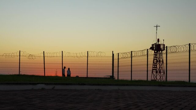 Two security guards walking the barb wire fence