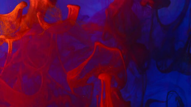 Orange ink flows into blue-tinted water.Abstract background