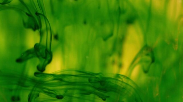 Green ink breaks up in water creating abstract structures, inky background