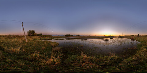 Spherical HDRi panorama of large swampy puddle near rustic dirt road at autumnal sunset