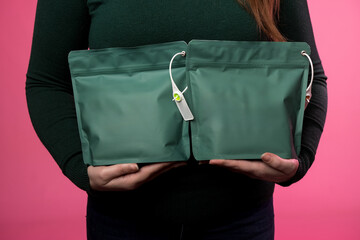 Woman presenting green resealable bags, suitable for food, cosmetics, or retail packaging. Vibrant...