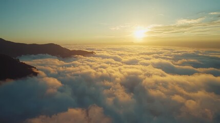 Fototapeta premium a stunning view of the sun rising above the clouds from the top of a mountain The sky is a beautiful mix of oranges, pinks, and purples, and the mountains are silh