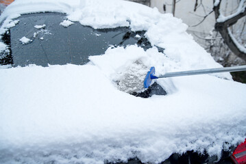 Snow covered car parked on street after snow storm. Side view of small vehicle or car snowed
