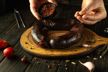 A chef adds dry aromatic spices to blood sausage before serving it for dinner. The sausage sits on...