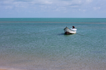 A fishing boat on the shores of Dhanushkodi Beach amidst the backdrop of a picturesque and tranquil coastline