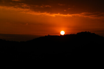 Fototapeta premium Golden hour, a very amazing sunset between the hills of trees and clouds