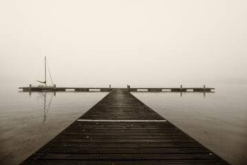 Obraz premium LANDSCAPE BY THE LAKE - A sailboat at the pier on a misty morning
