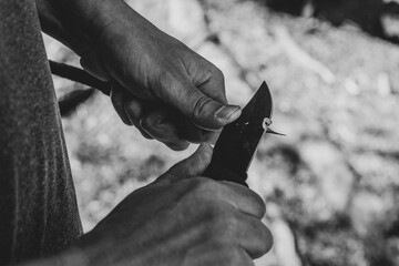 Sharpening a stick with a knife, black-and-white