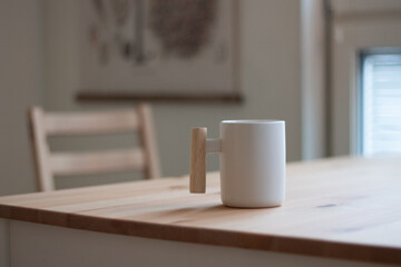 A coffee mug with a wooden handle on a plain wooden table