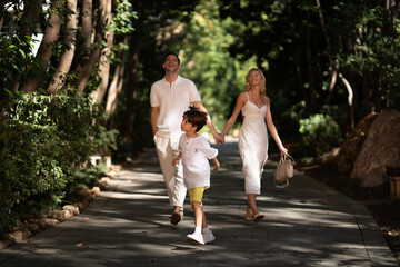 Obraz premium A joyful family walking together through lush greenery, enjoying the fresh air and peaceful atmosphere of nature.