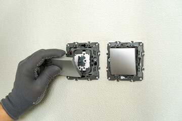Electrician hands installing electric light switch. Electrical switch key insert. Replacing....