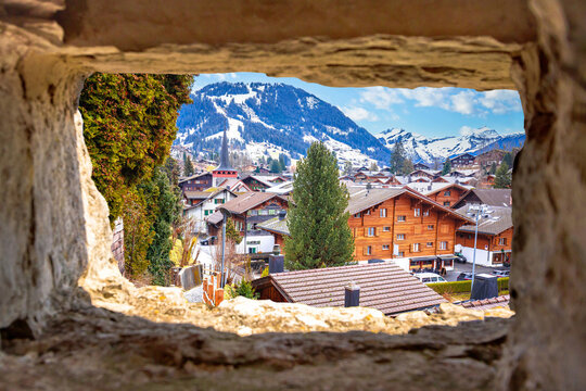 Idyllic Alpine village of Gstaad view through stone window, luxury winter destination