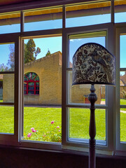 Exterior of a Tuscan farmhouse shot from a window with a standard lamp in the foreground