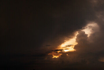 A dark sky with a bright sun peeking through the clouds