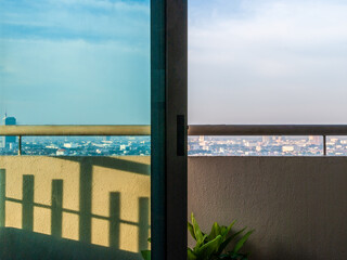 A city skyline is reflected in the glass of a balcony