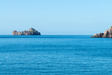 Naklejka premium rock on the calm sea on a sunny day