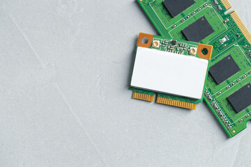 Wi-Fi card and RAM chip on grey table, top view. Space for text