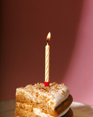 one candle close up on cake on pink background