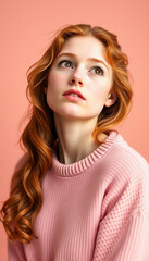 Fototapeta premium Soft portrait of a young woman in a pink sweater, looking up thoughtfully, symbolizing gentle coziness