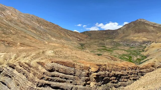 Chicham village and spiti valley in the distance isolated by high himalayas under bright sky in summer near chicham himachal pradesh, India.