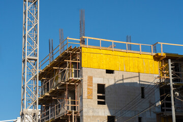 Crane and building under construction against blue sky