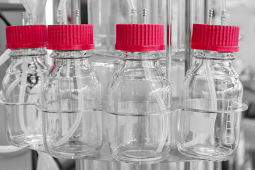 Four clear glass bottles with red lids. The lids are red and have a white stripe medical pharmaceutical laboratory