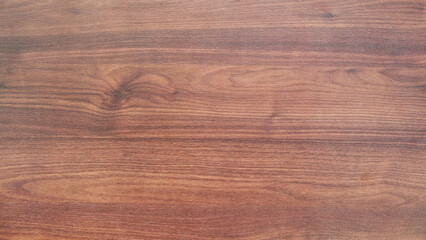 A wooden surface with a grain pattern. The wood is brown and has a natural texture. The surface is smooth and has no visible blemishes