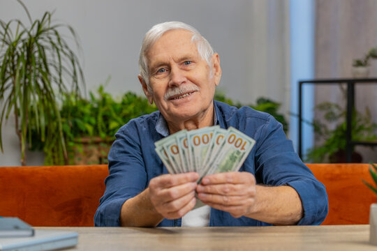 Planning family budget. Happy senior man counting money cash calculate domestic bills at home. Mature old grandfather satisfied of income salary pension and saves money for planned vacation gifts