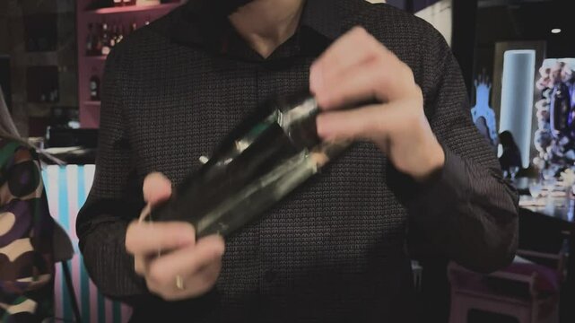 Skilled bartender prepares shakes alco beverage shaker. Alcohol drink craftsmanship. Hands expertly mix ingredients, art of cocktail making. Nightlife, night club, night bar or pub. Mixology expertise